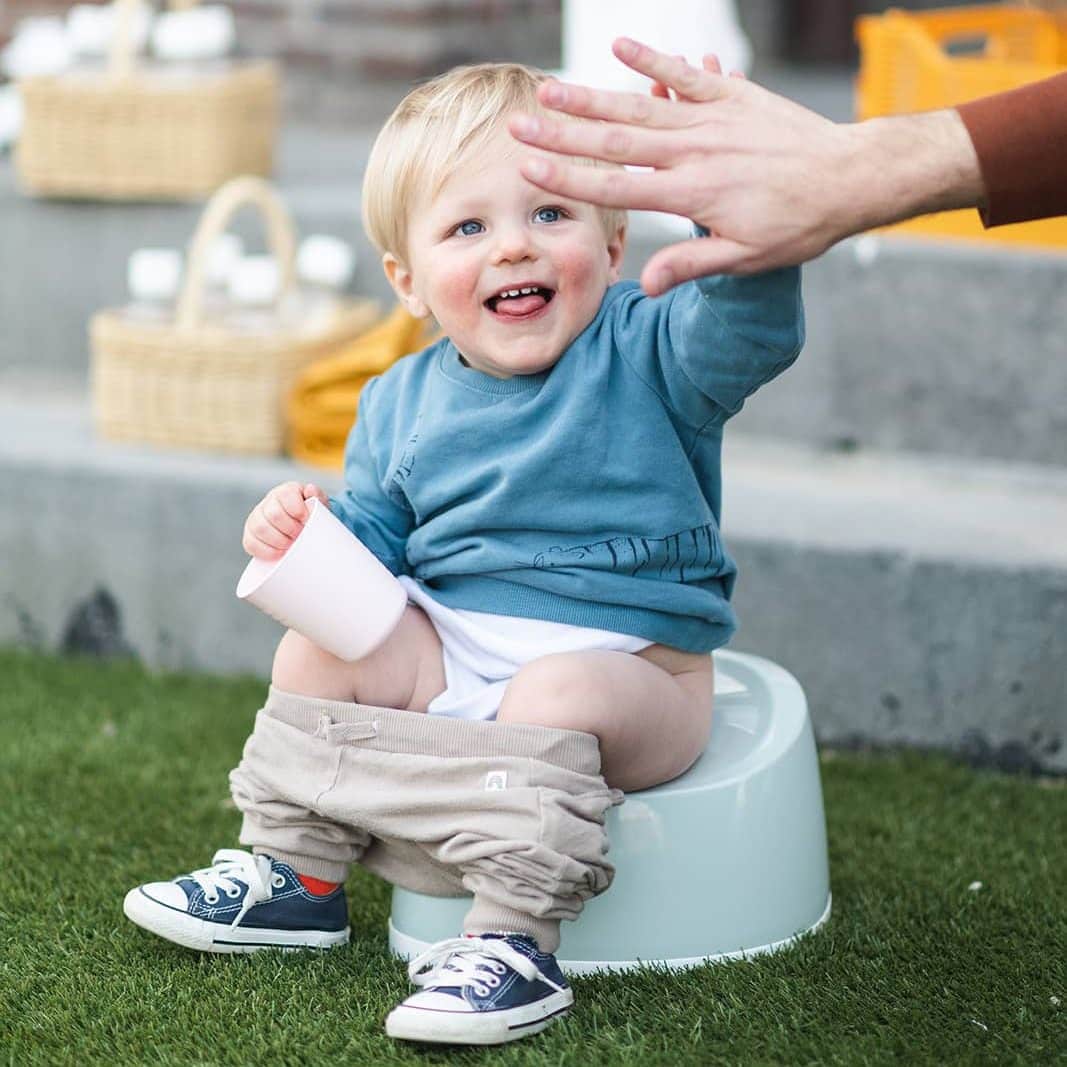 Peuter op het potje geeft high five 