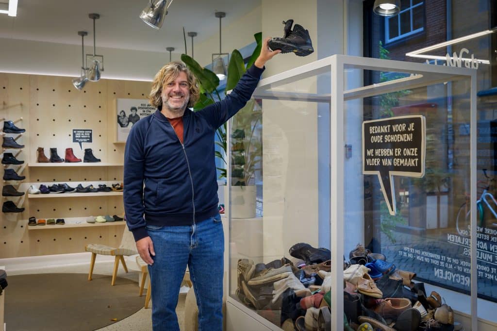 Man gooit een schoen in een bak met schoenen waarvan de materialen gerecycled gaan worden.