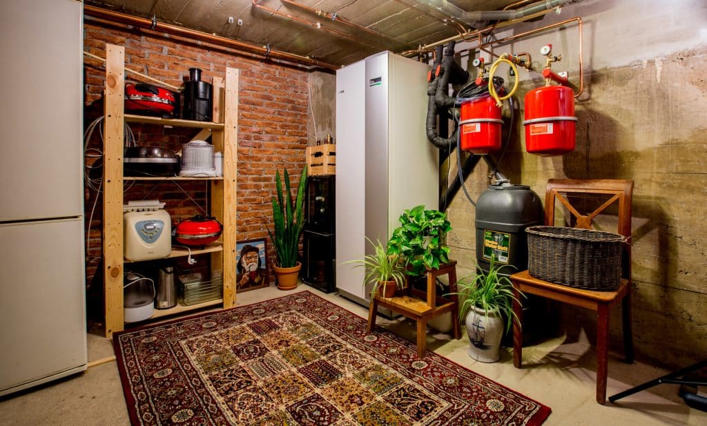 Bijkeuken of schuur met voorraadkasten, een boiler en binnenunit voor een warmtepomp.